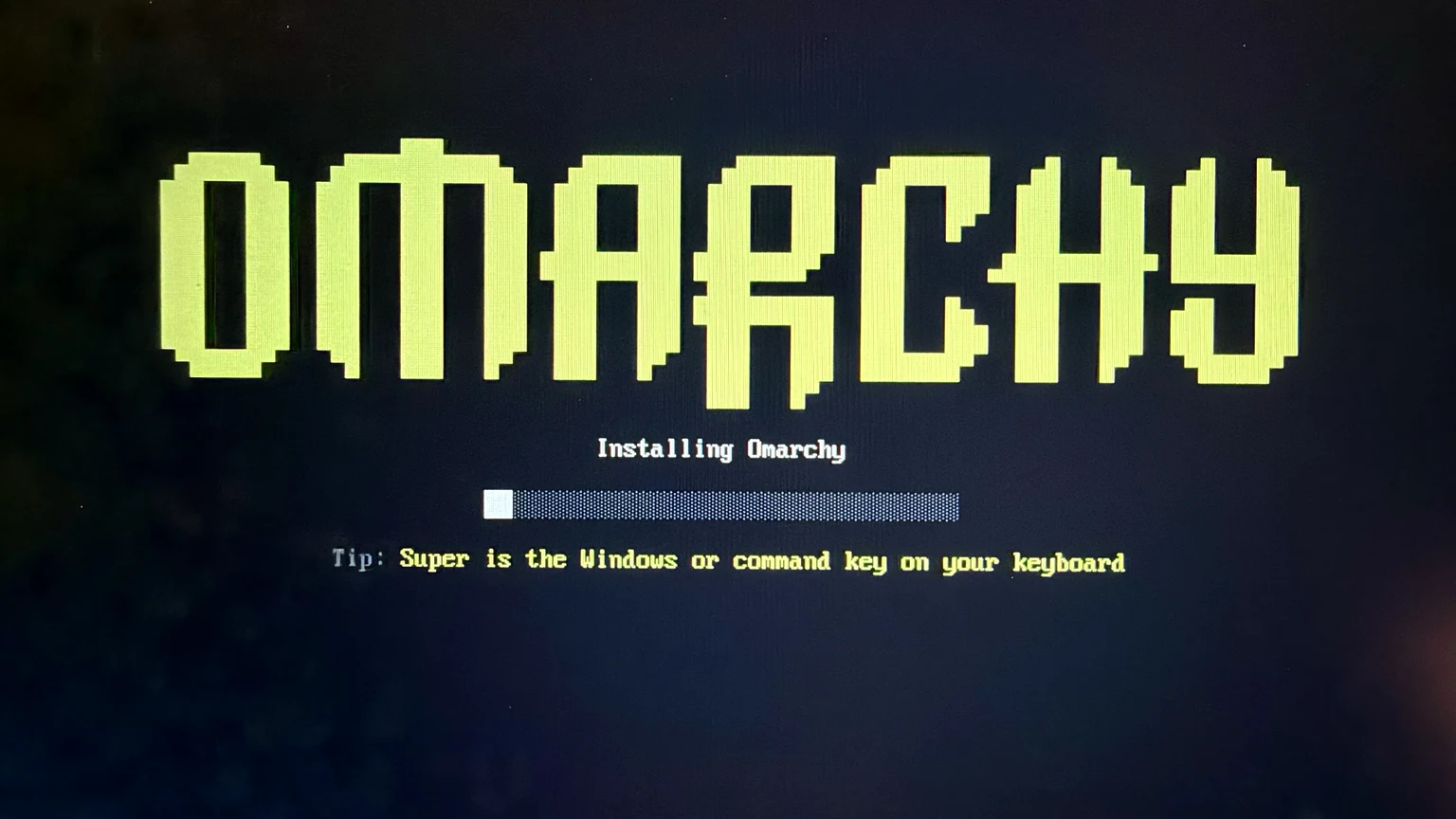 Omarchy installer showing the lime-green Omarchy logo, installation progress bar, and Super-key tip